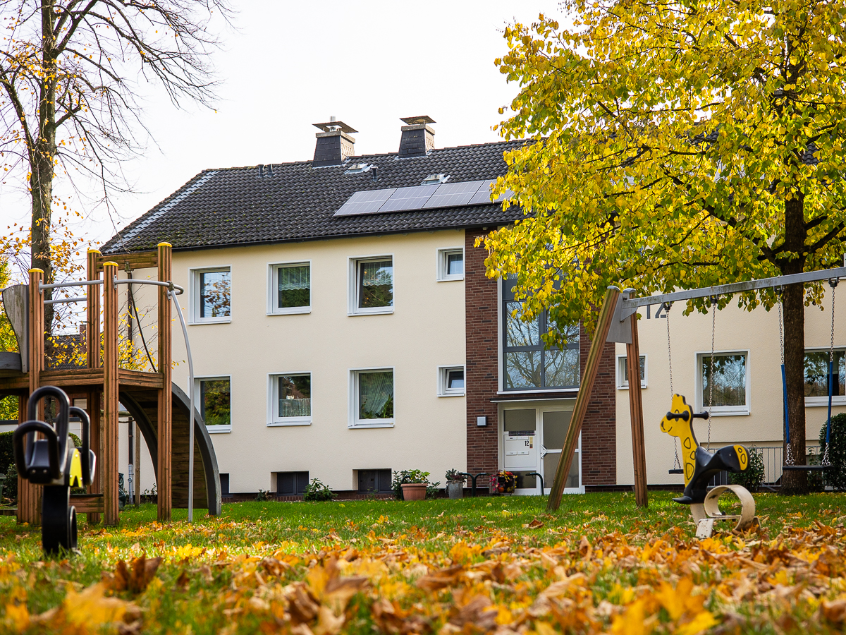 Innenhof mit Laub auf dem Boden. Im Hintergrund ist das modernisierte Gebäude zu sehen.