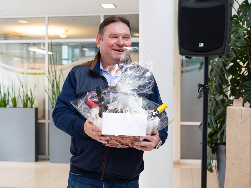 Georg Moch hält einen Präsentkorb in den Händen und lächelt