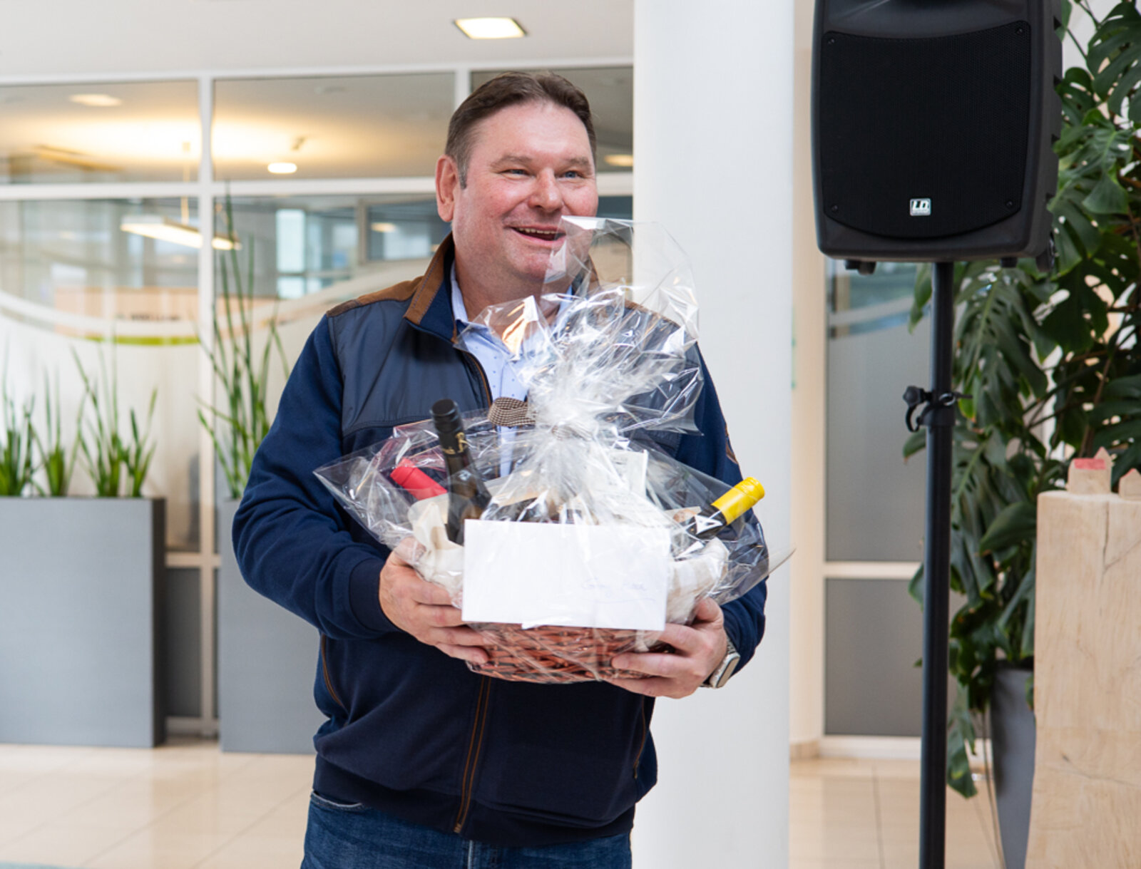 Georg Moch hält einen Präsentkorb in den Händen und lächelt