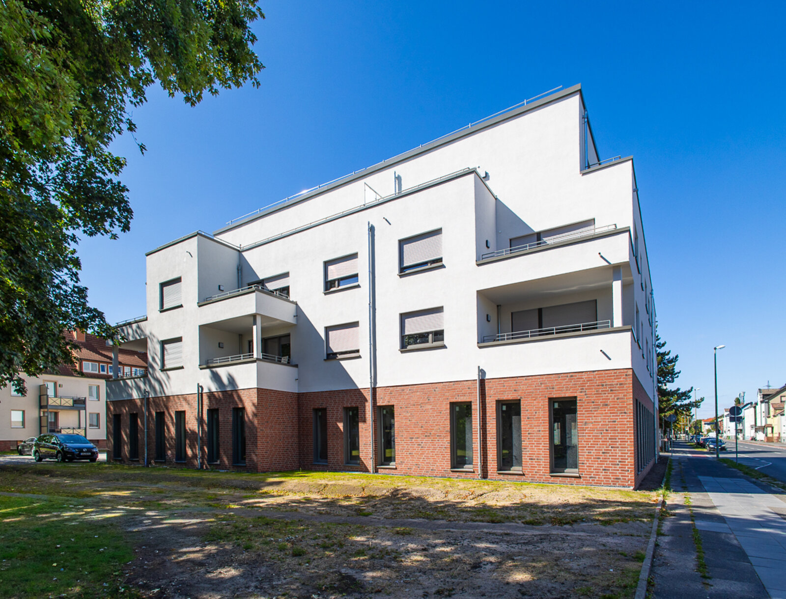 Neu errichtetes Mehrfamilienhaus mit Gewerbeflächen im Erdgeschoss und Wohnungen in den oberen Etagen.