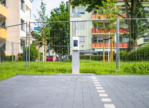 Neue E-Ladesäule, umgeben von Grünflächen und Mehrfamilienhäusern.