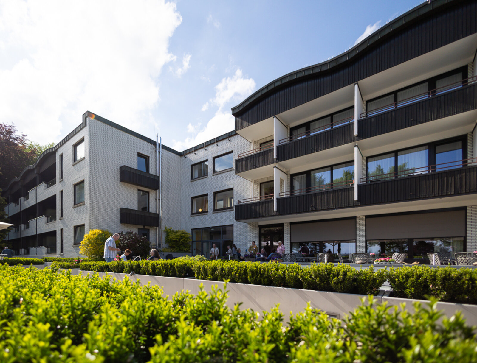 Außenansicht des Tagungshotels mit Balkonen und begrünter Außenanlage bei sonnigem Wetter.