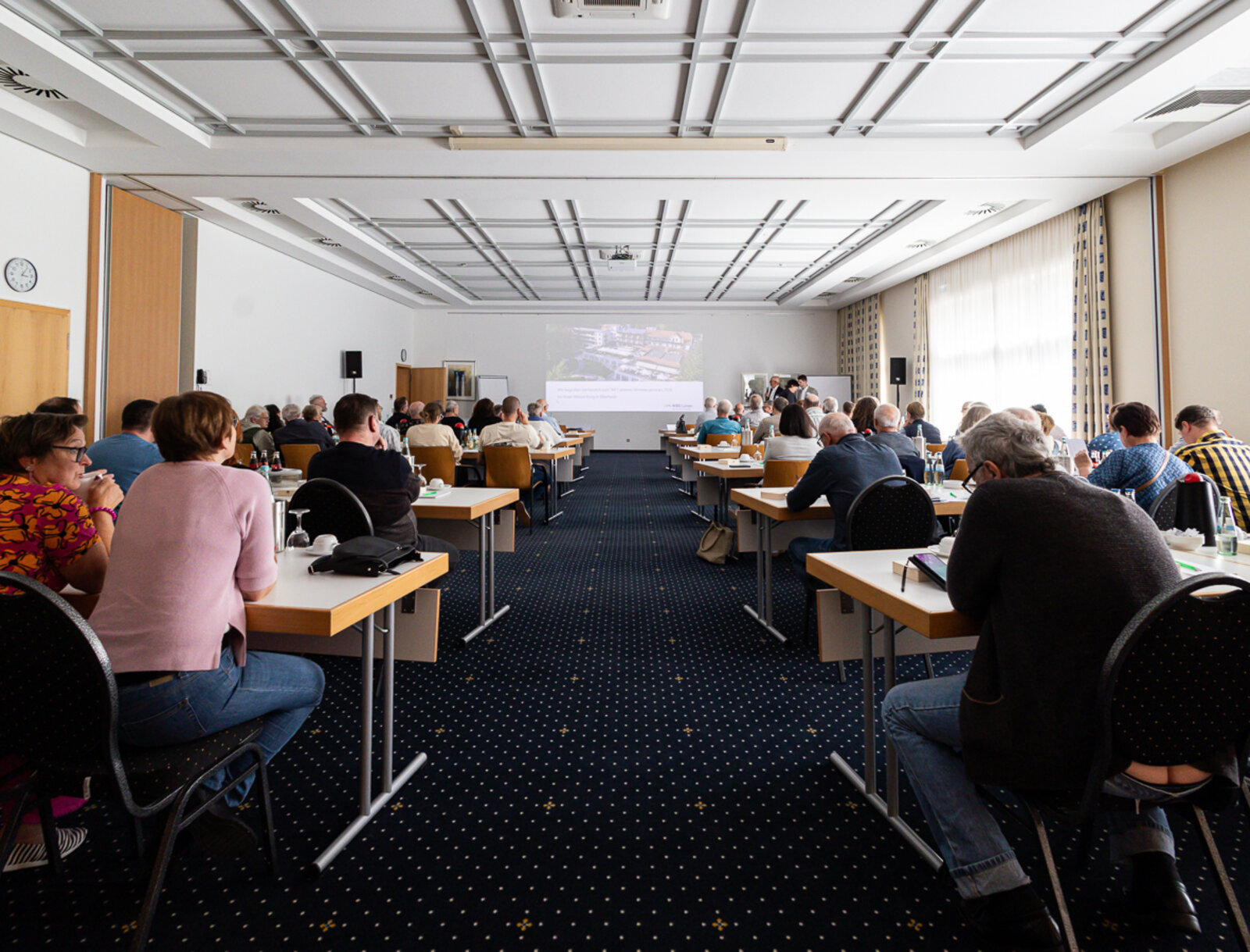 Blick in den Seminarraum mit zahlreichen Teilnehmenden während einer Präsentation beim Vertreter*innenseminar in Billerbeck.