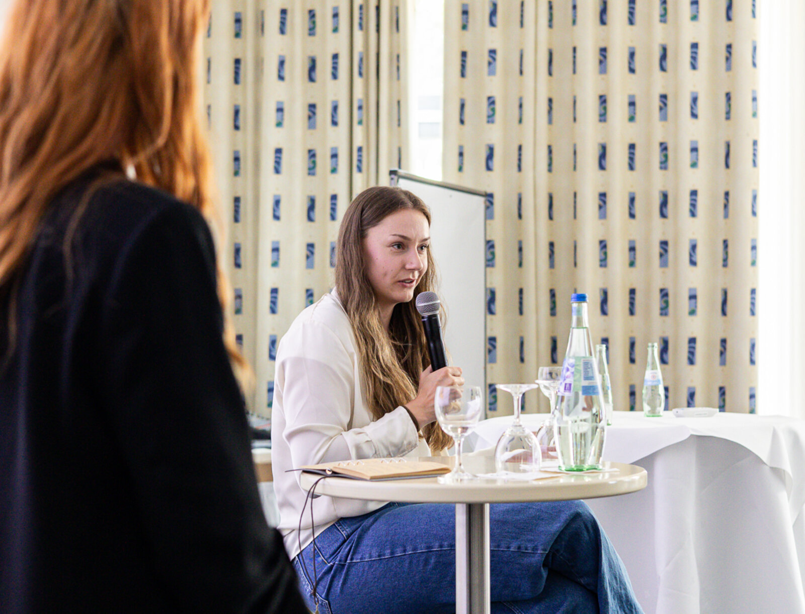 Bob-Olympiasiegerin Laura Nolte spricht beim Vertreter*innenseminar mit Mikrofon an einem Tisch vor Publikum.