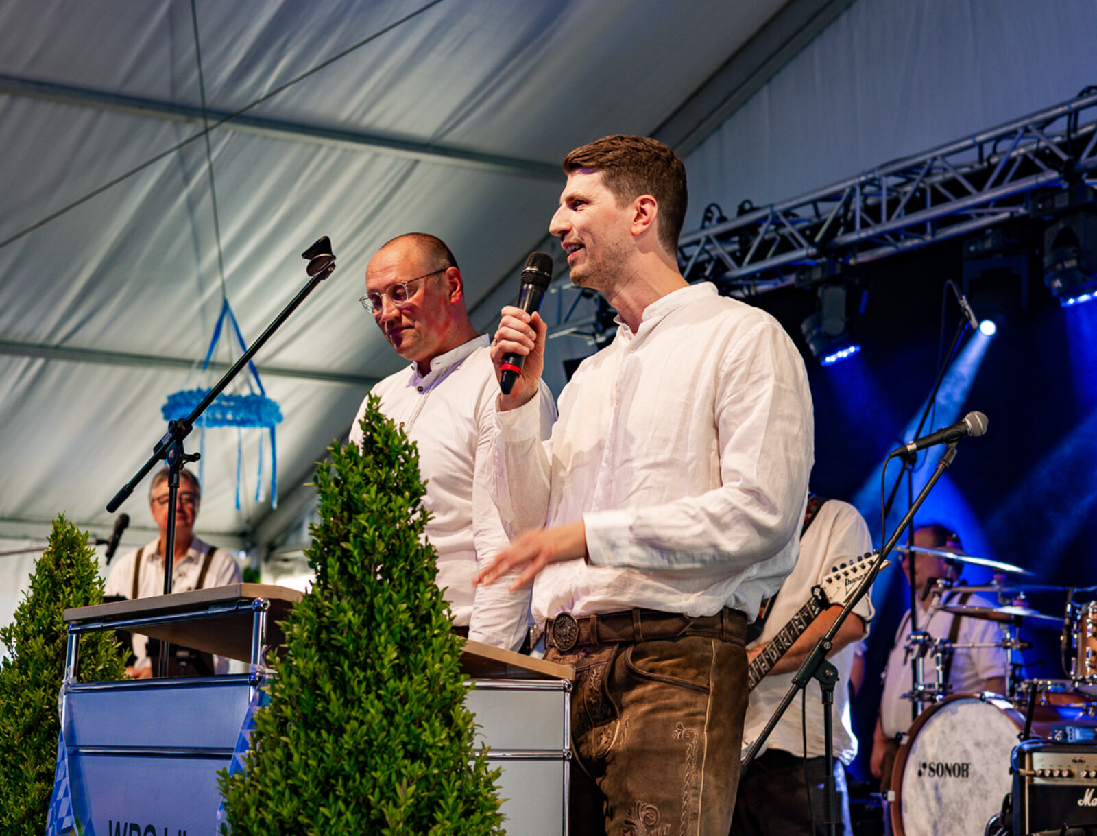 Aufsichtsratsvorsitzender Prof. Dr. Christian Melchers und Vorstand Jan Hische begrüßen die Gäste auf der Bühne, im Hintergrund steht die Live-Band.