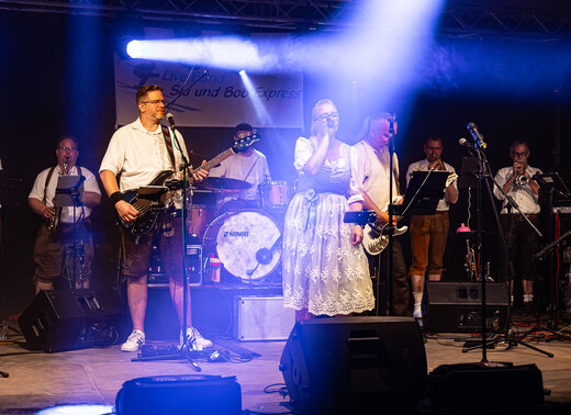 Die Band Ski und Bob Express spielt mit Gesang, Gitarren und Blasinstrumenten auf der Bühne.