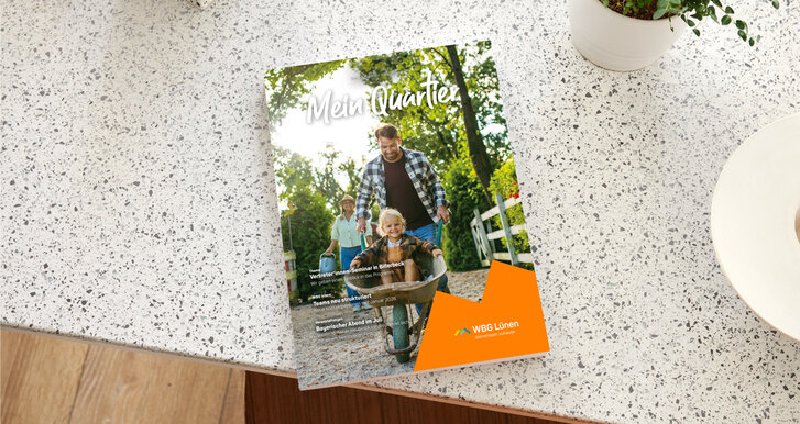 Ausgabe des Magazins „Mein Quartier“ der WBG Lünen liegt auf einer Tischoberfläche. Auf dem Titel ist eine Familie im Grünen zu sehen.