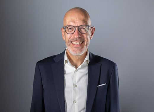 Portrait von Dr. Felix Prinz vor grauem Hintergrund.