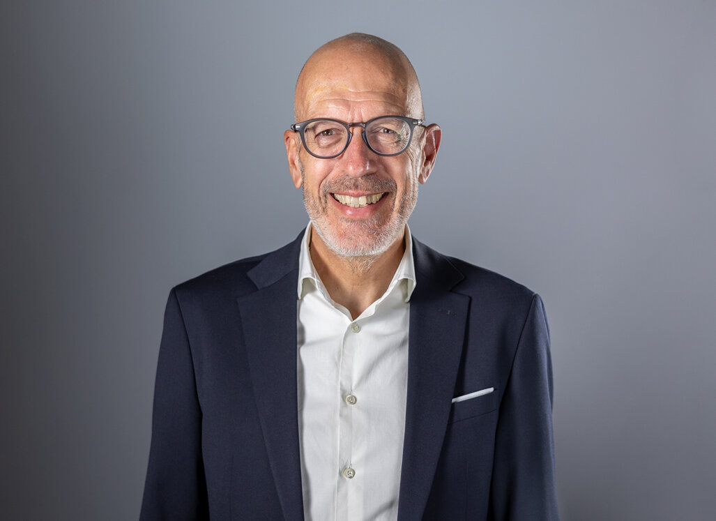 Portrait von Dr. Felix Prinz vor grauem Hintergrund.