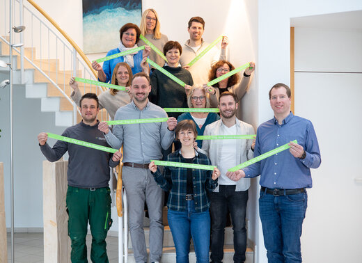 Mitarbeitende der WBG Lünen stehen gemeinsam im Treppenhaus und halten grüne Bänder mit der Aufschrift „Tag der Kinderhospizarbeit“.