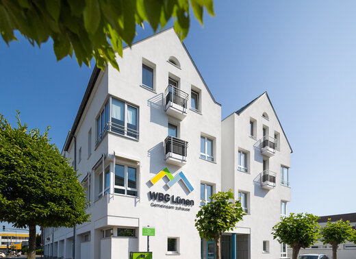 Verwaltungsgebäude der WBG Lünen mit weißer Fassade und dem Unternehmenslogo an der Gebäudeseite.