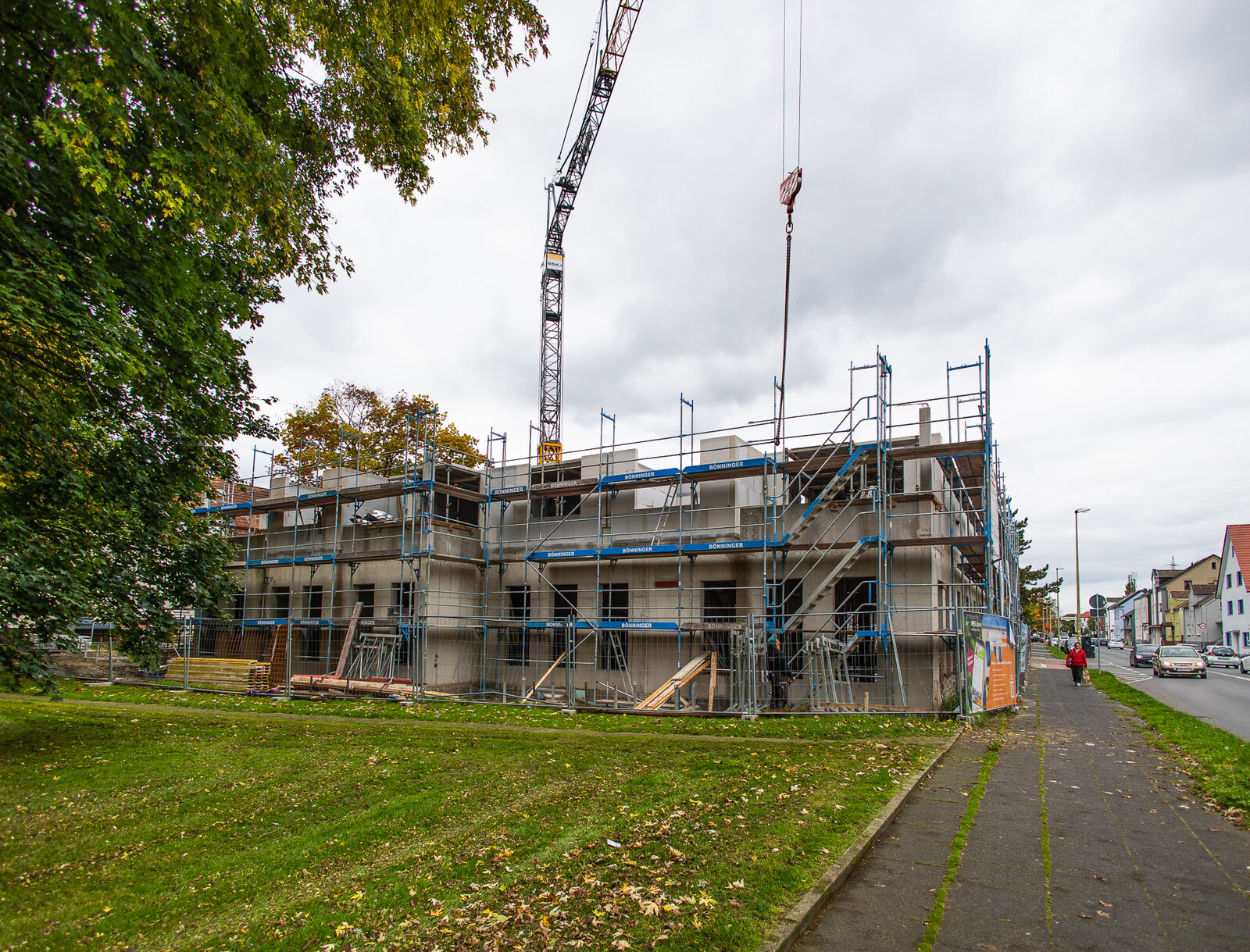Neubau eines Mehrfamilienhauses in Lünen mit Baugerüst und Baukran, aufgenommen von der Straße entlang eines Gehwegs und einer Grünfläche.