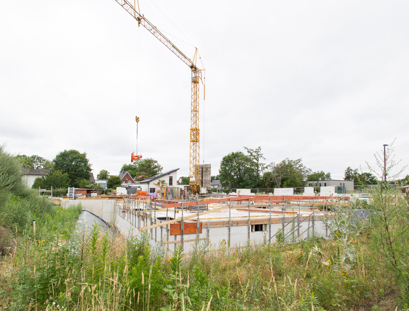 Baufortschritt des Neubauprojekts am Johannes-Ahland-Weg in Lünen mit Kellergeschoss und Baukran.