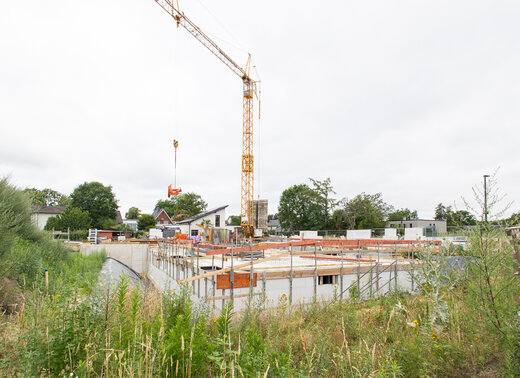 Baufortschritt des Neubauprojekts am Johannes-Ahland-Weg in Lünen mit Kellergeschoss und Baukran.