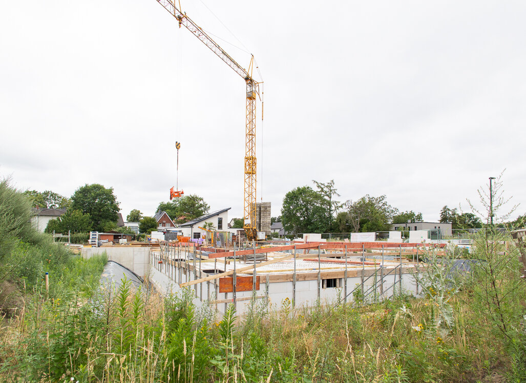 Baufortschritt des Neubauprojekts am Johannes-Ahland-Weg in Lünen mit Kellergeschoss und Baukran.