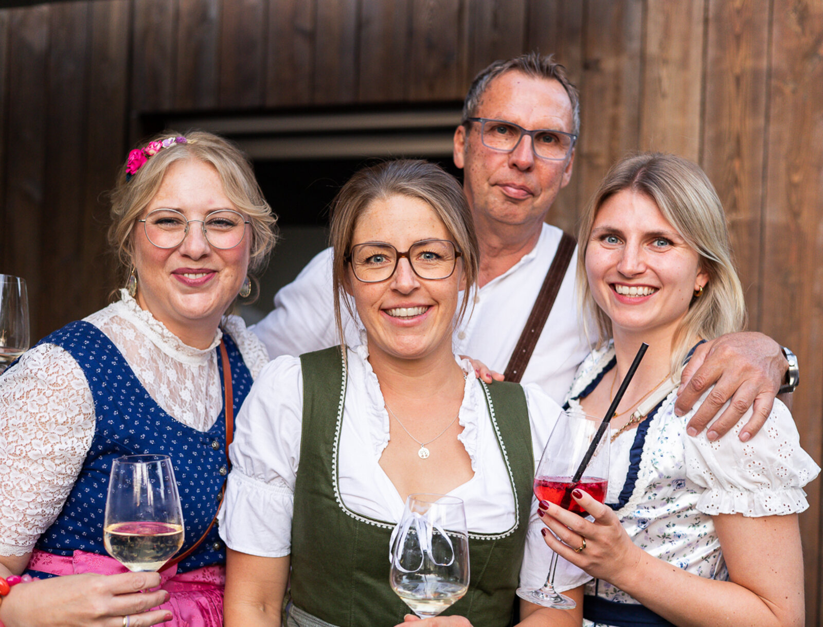 Vier Gäste stehen gemeinsam für ein Foto und halten Getränke in den Händen.