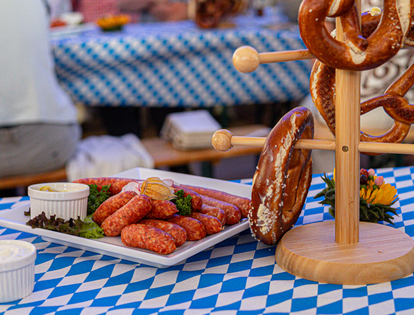Brezeln und kleine Mettwürstchen auf einem blau-weiß gedeckten Tisch beim Bayerischen Abend.