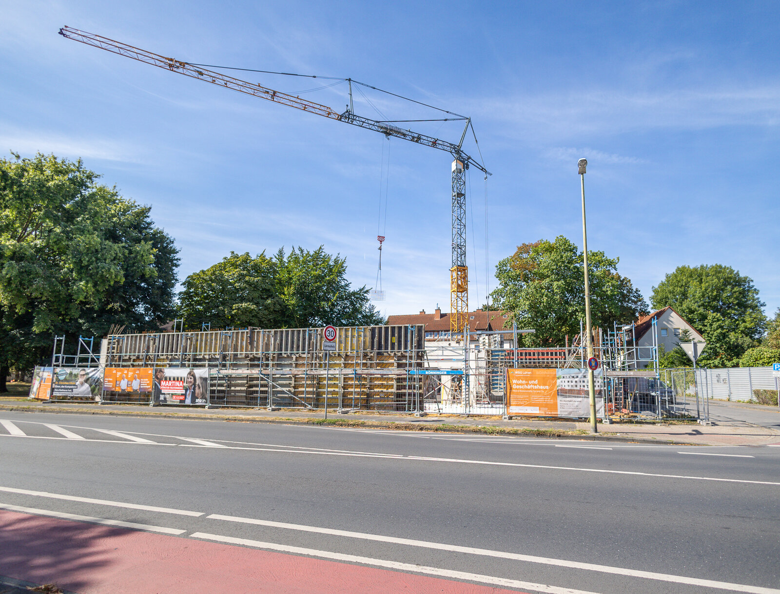 Baustelle eines Wohn- und Geschäftshauses an der Kleinen Bebelstraße in Lünen mit Baukran, Schalungen und Bauzaun entlang einer Straße.